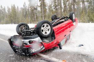 A red truck is rolled over in a snowy area after losing control