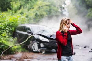 woman holds head and talks on phone after auto wreck