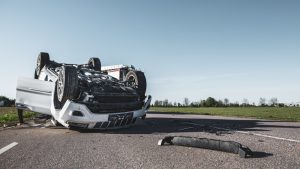 flipped-over white car with separated bumper
